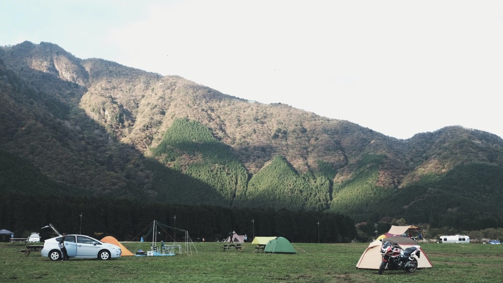 people camping in their cars in front of Japanese mountains