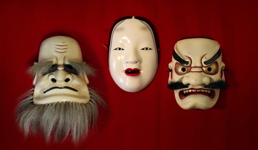 three Japanese masks on a red wall